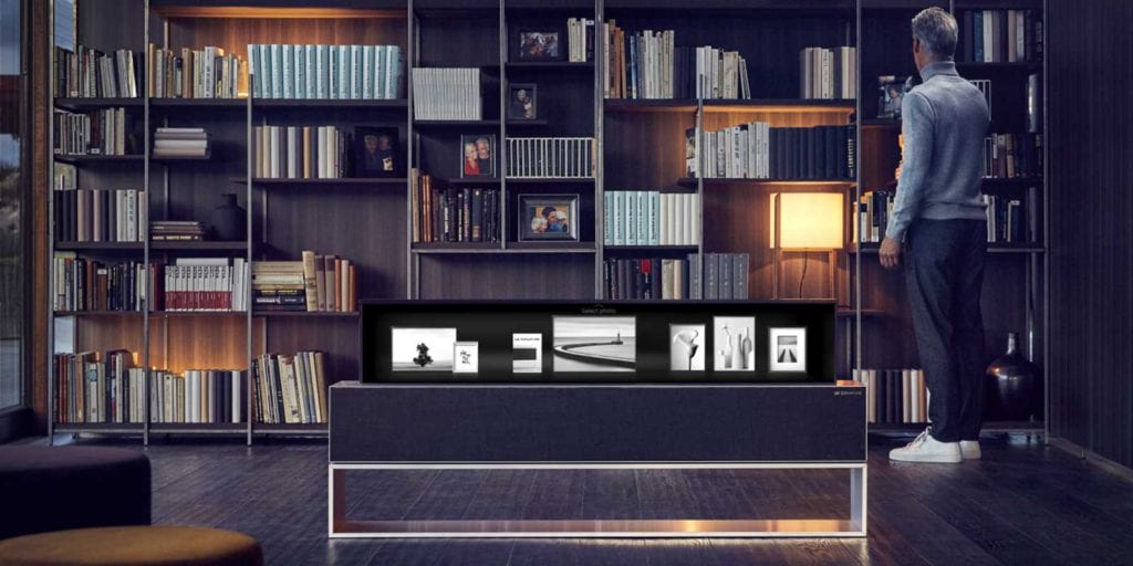 Téléviseur enroulable dans un salon, écran partiellement déroulé